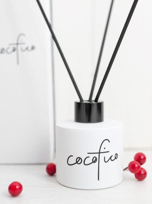black and white cocofico reed diffuser with red berries in the foreground